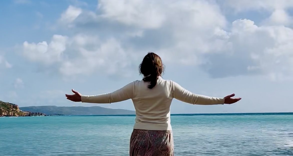 Femme face à la mer, les bras ouverts – atelier La VoiX du Cœur